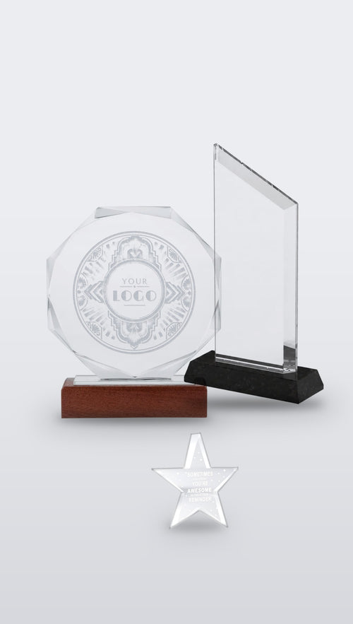 Group of custom awards: engraved octagonal crystal on wooden base, trapezoid crystal on black base and clear acrylic star