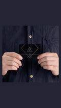 Black metal business card held in hand with sample engraving