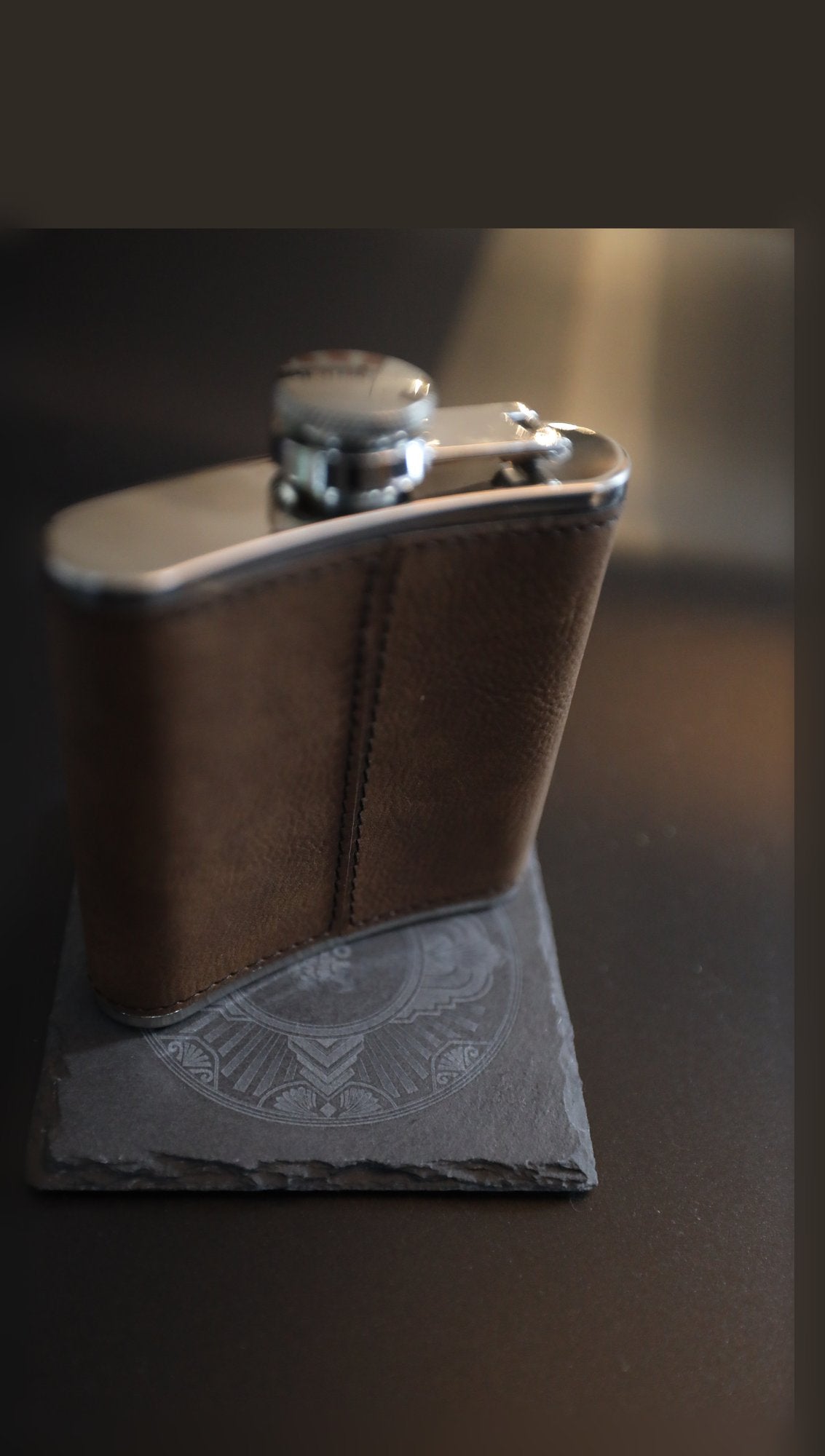 Plain brown leather hip flask on a slate coaster, unengraved