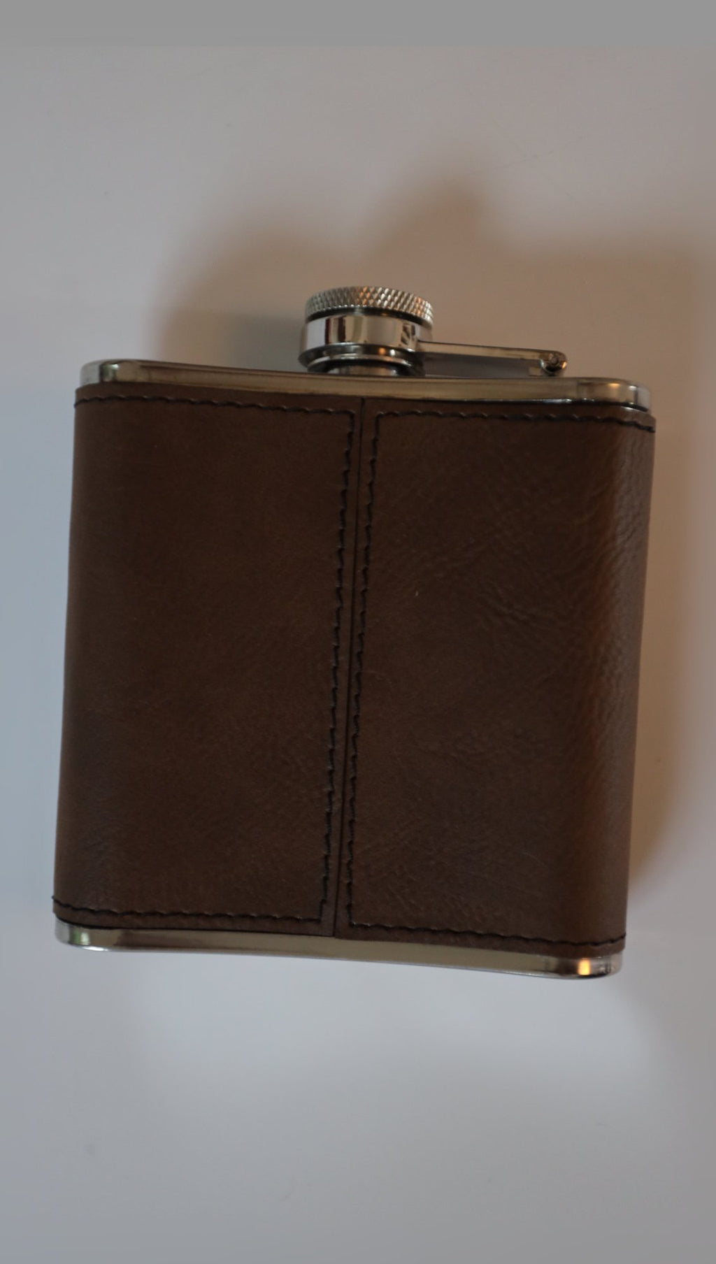 Leather hip flask upright on light background