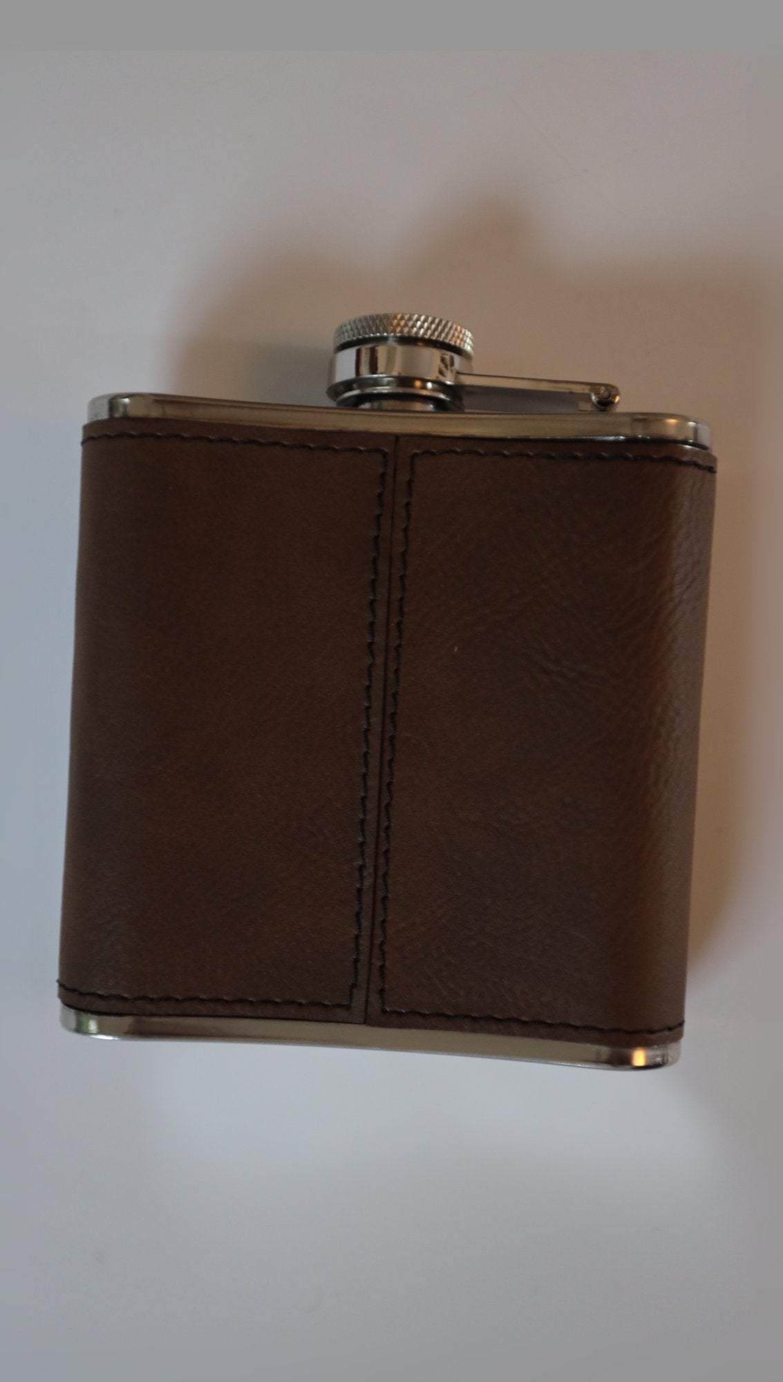 Leather hip flask upright on light background