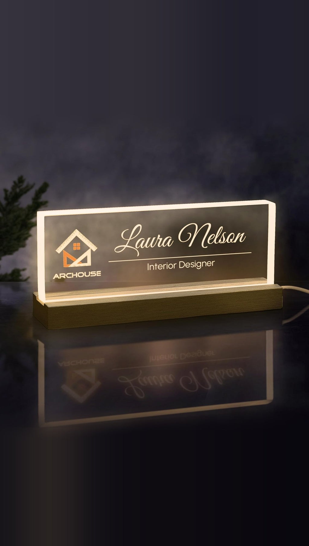 Sample design: lit acrylic desk nameplate on a wooden LED base, engraved with an Archouse logo, Laura Nelson and Interior Designer glowing warm white