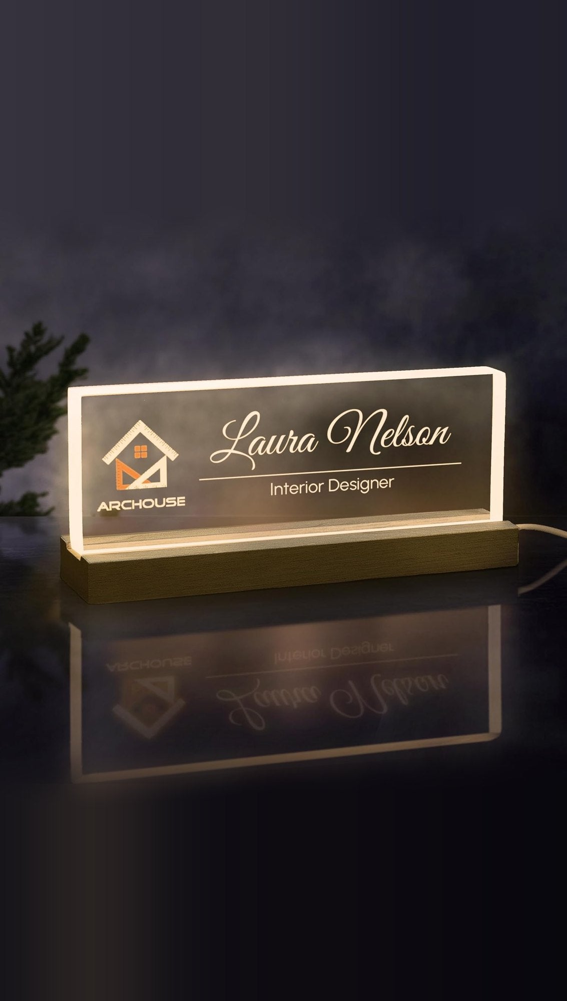 Sample design: lit acrylic desk nameplate on a wooden LED base, engraved with an Archouse logo, Laura Nelson and Interior Designer glowing warm white