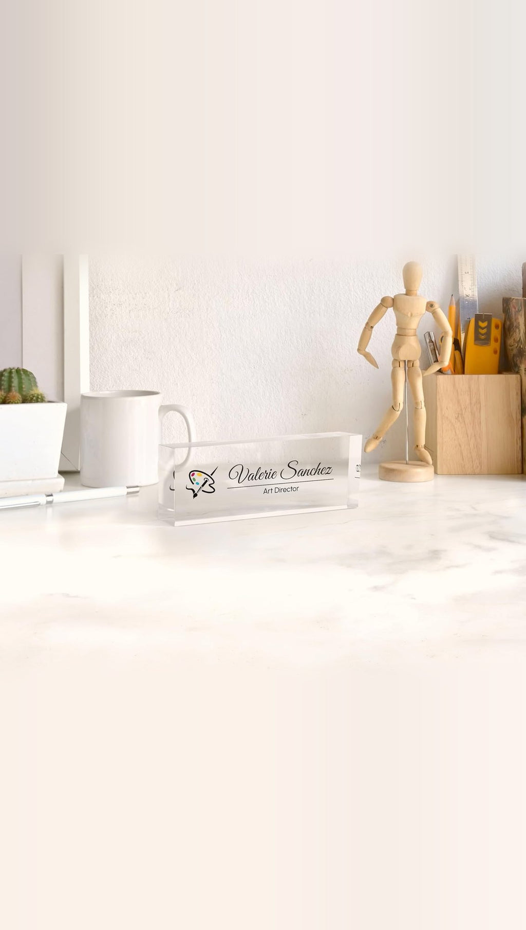 Sample design: clear acrylic desk nameplate reading Valerie Sanchez, Art Director, on an office desk