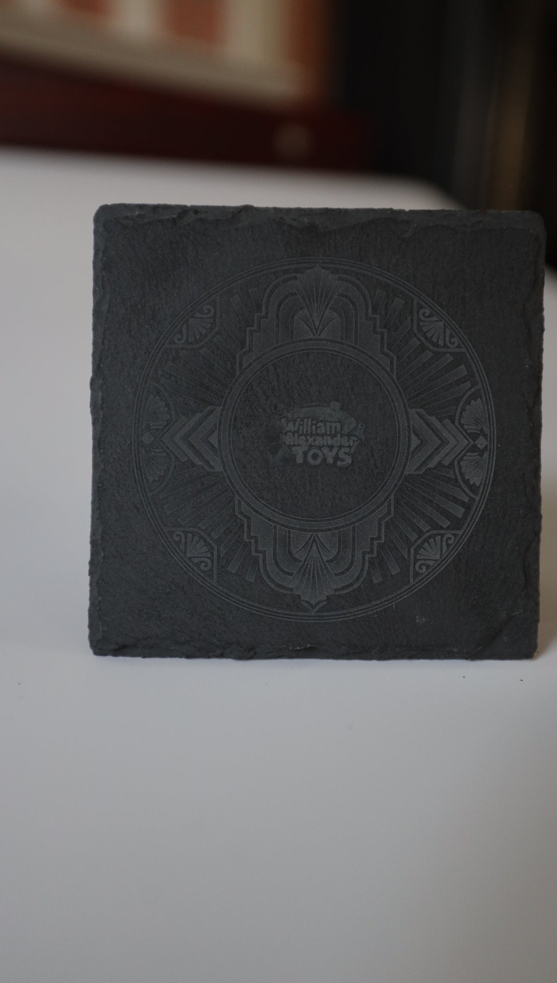 Engraved slate coaster with Art Deco design, standing upright