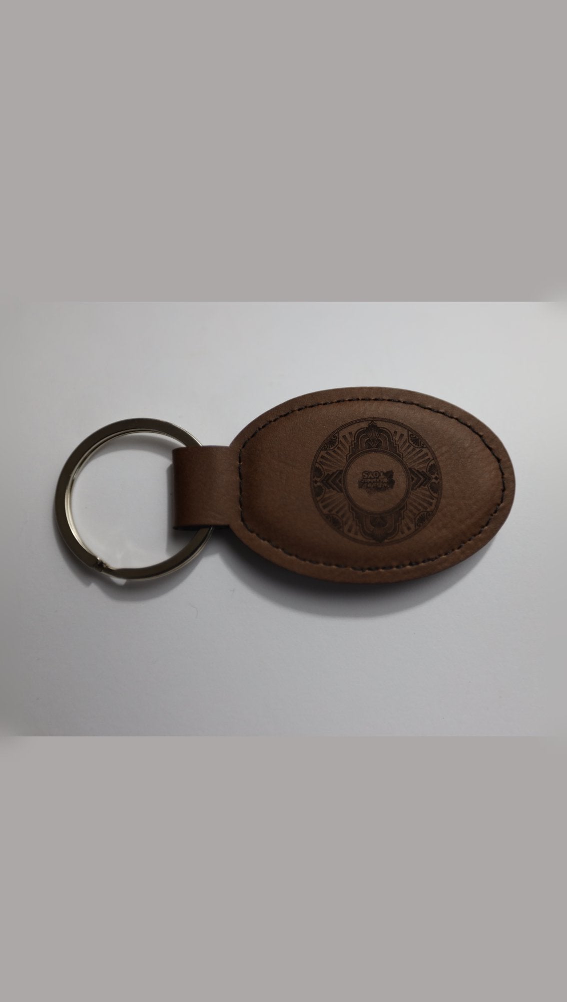 Oval faux leather keyring with sample engraving, angled view