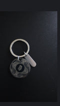 Stainless steel disc keyring with sample engraving and blank tag, on black