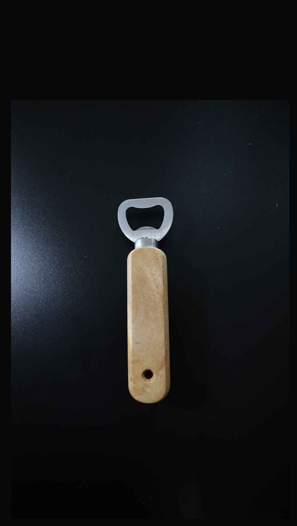 Plain wooden handle bottle opener with steel head, unengraved, upright on black