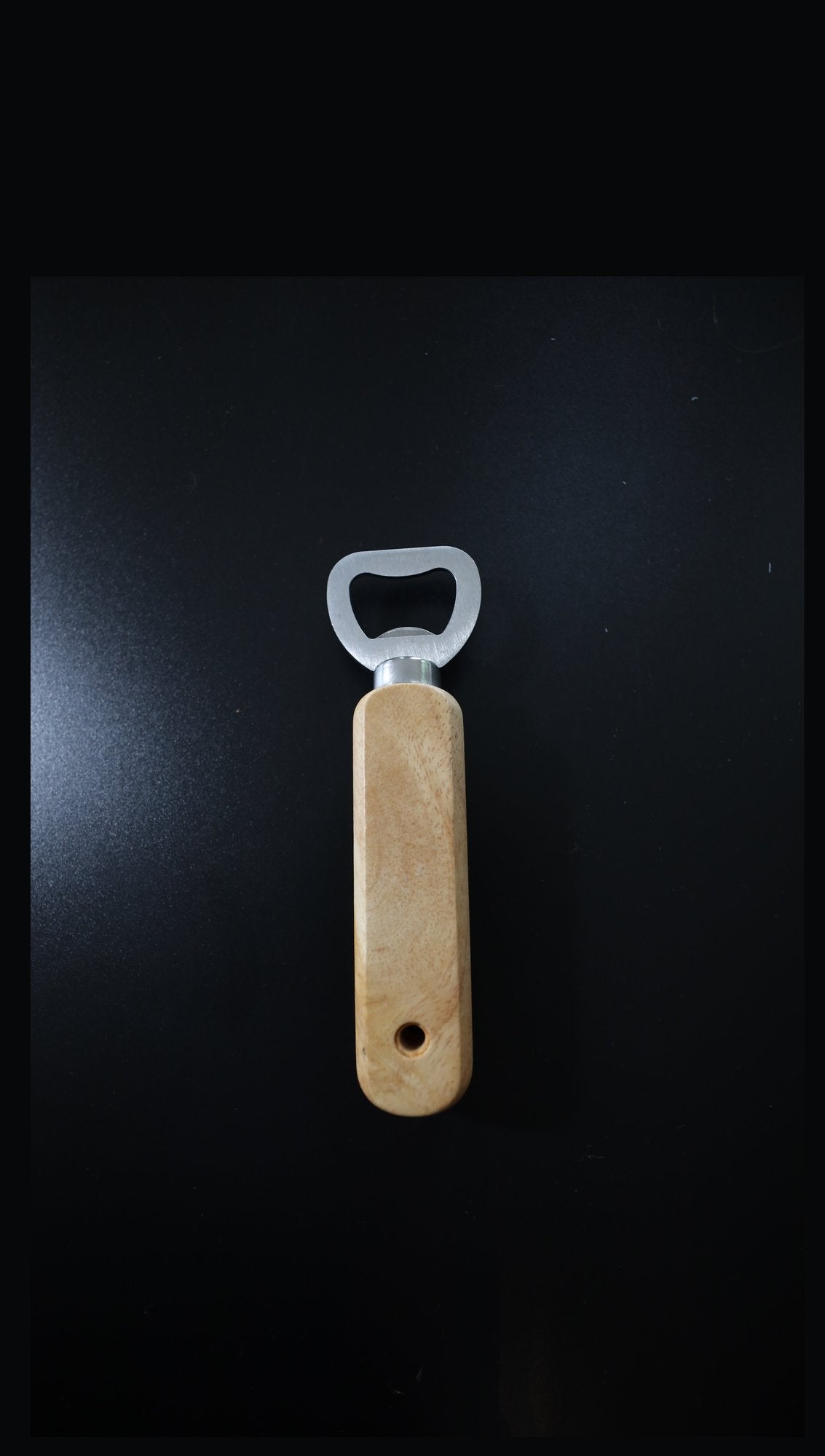 Plain wooden handle bottle opener with steel head, unengraved, upright on black