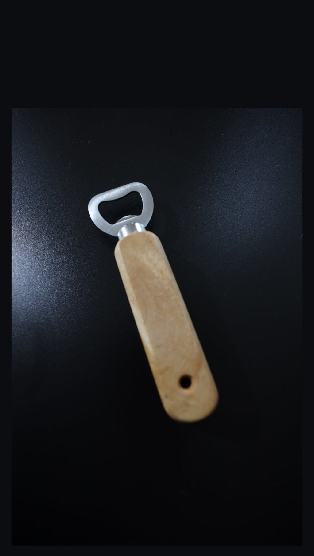 Wooden handle bottle opener, plain angled view on black