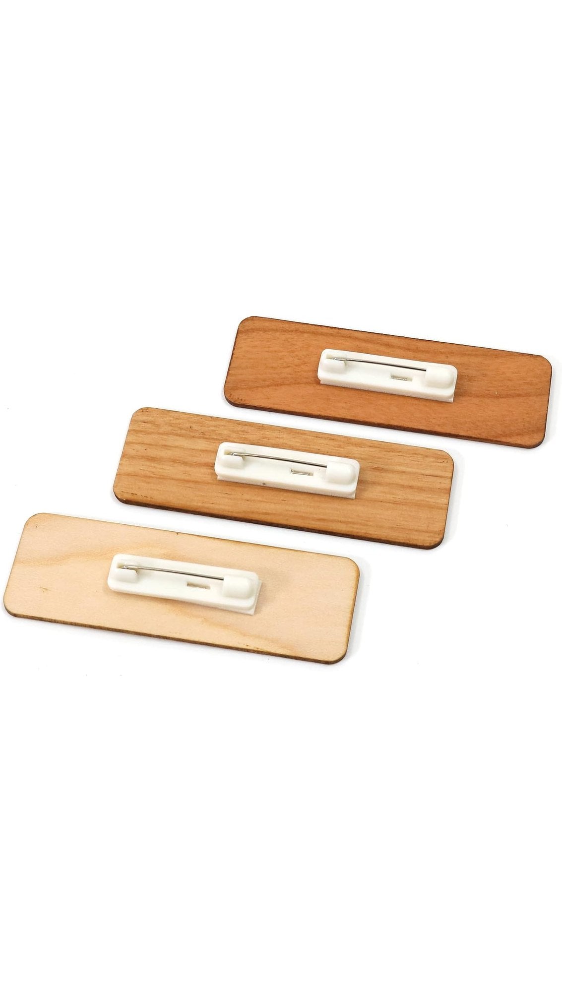 Back of the wooden name badges in three wood tones, each with a safety-pin back