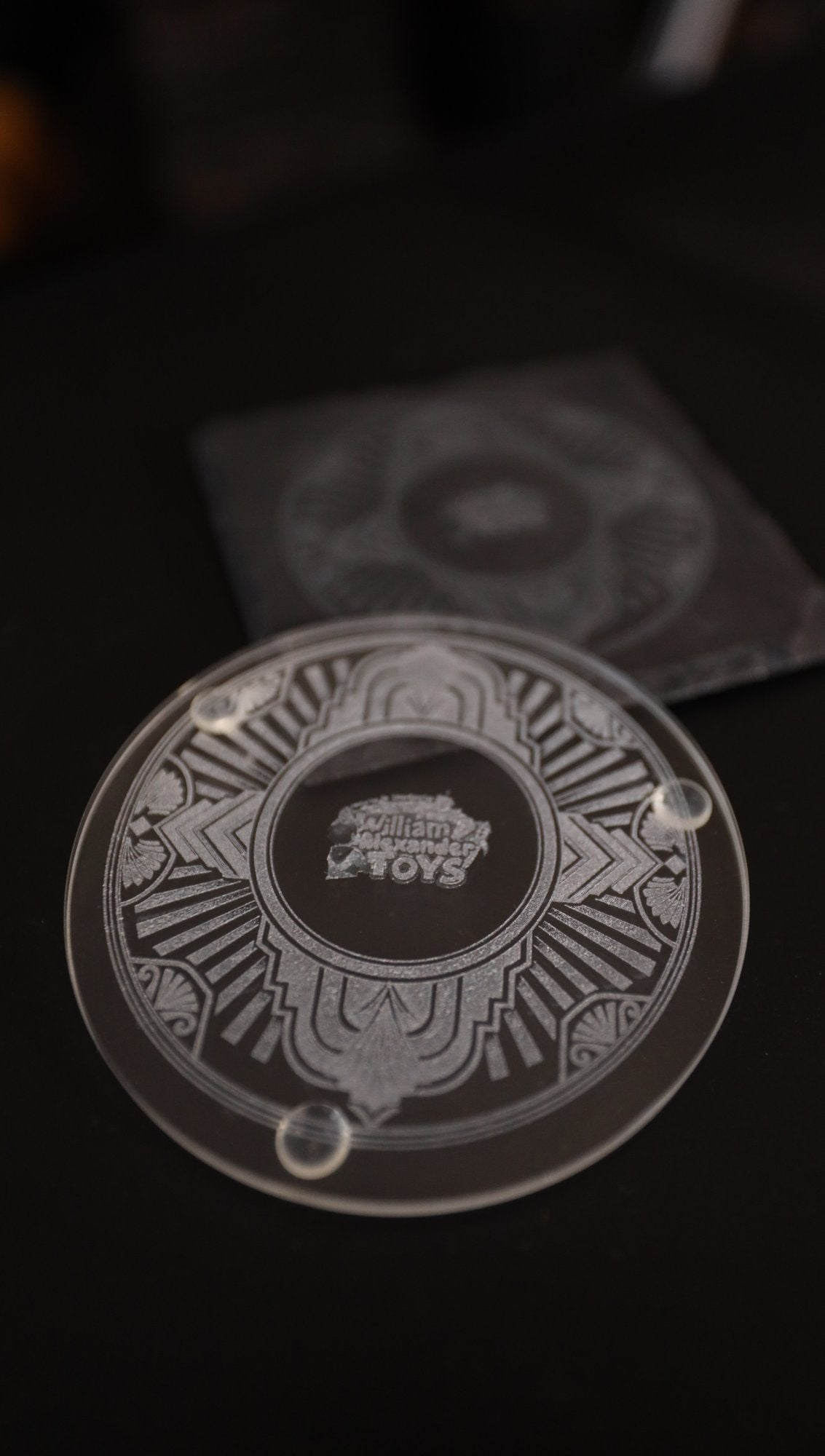 Etched glass coaster in front of a slate coaster